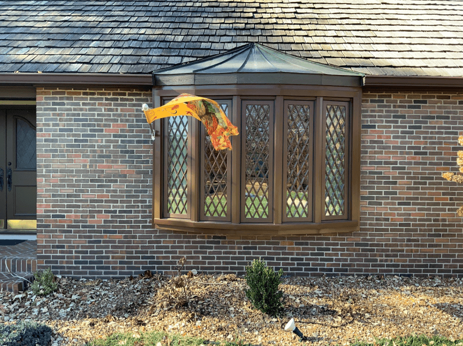 Orange flag flying outside a brick house with diamond-pane windows and wooden shingled roof.